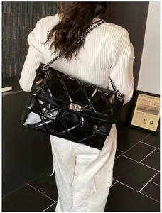 Side view of large black quilted patent leather bag with silver chain and crystal lock