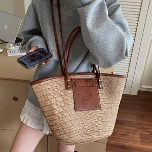 Large woven straw tote bag with brown leather trim shown on a model for vacation style