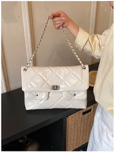 Detail showing high-gloss patent leather texture and quilted diamond pattern with chain strap