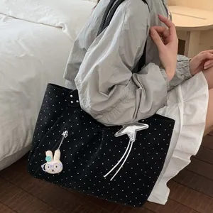 Black canvas tote bag with white polka dots, silver star charm, and rabbit doll pendant