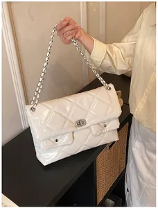 Macro shot of large quilted glossy faux leather shoulder bag with chain straps