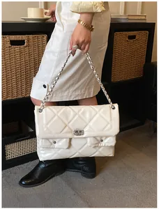 Lifestyle shot of white quilted patent leather chain bag with silver twist lock and pockets