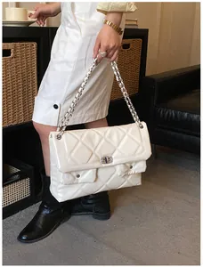 Close-up of white patent leather crossbody bag with quilted pattern and silver chain strap