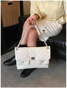Macro detail of white quilted texture and metallic chain strap on a small flap bag