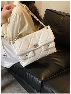 Detail of cream quilted leather messenger bag featuring double front pockets and chain strap