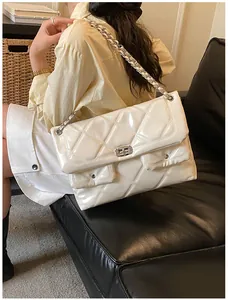 Close-up of white quilted patent leather crossbody bag with silver chain and dual pockets