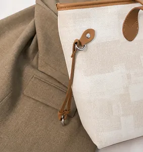 Detail view of canvas tote side rings with brown leather trim and metal hanging rings