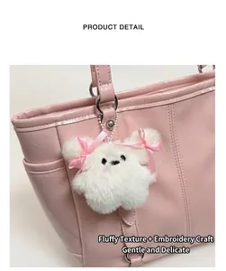Detail of white plush dog charm with pink bows on shiny pink leather tote bag