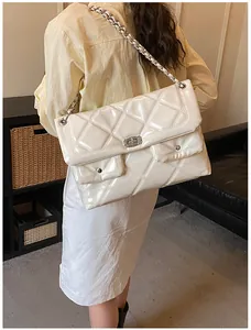 Detail of cream quilted chain bag featuring dual front pockets and glossy leather finish