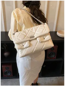 Close-up of quilted cream leather shoulder bag with glossy finish and chain strap