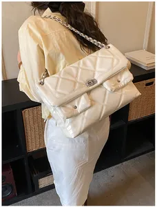 Detail of white quilted crossbody bag with glossy finish and dual front pockets