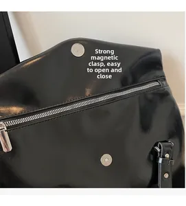 Detail view of strong magnetic buckle and metal zipper on black leather tote bag