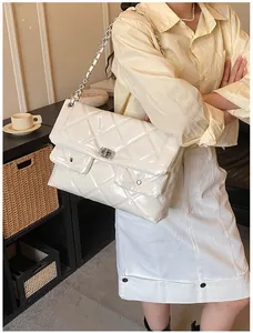 Detailed view of white quilted faux leather bag with silver chain and dual front pockets