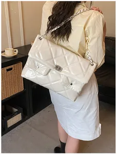 Detail view of white quilted patent leather crossbody bag with silver chain and twist lock
