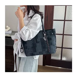 Detail of large tote bag with geometric pixel pattern and silver metal pendant on model
