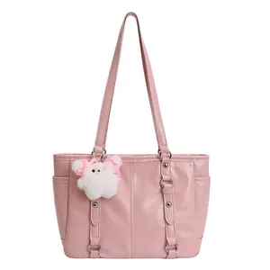 Detail of pink glossy leather tote bag with rivet straps and white cat plush charm