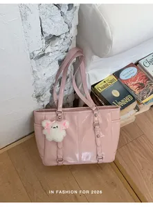 Pink glossy shoulder bag detail featuring metallic buckles and white plush puppy charm