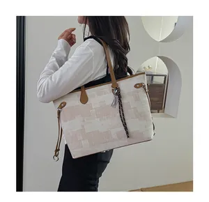 Side view of large canvas tote bag with brown leather handles worn by a model