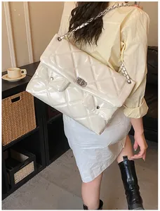 Detail showing cream quilted leather crossbody bag with silver chain and dual front pockets