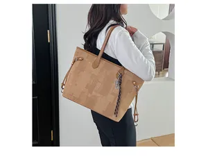 Detailed view of khaki patchwork tote bag with braided metal pendant and slim handles