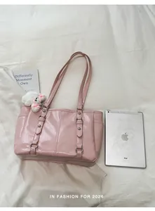 Detail of light pink patent leather tote bag with silver studs and white plush bear charm