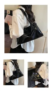 Detail view of glossy black tote bag with wide shoulder strap and metallic rivet hardware