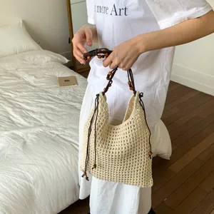 Minimalistische cremefarbene Flecht-Tasche mit Holzperlen-Trägern und Quasten-Details
