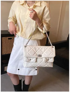 Close-up of white quilted leather crossbody bag with silver chain strap and metal lock