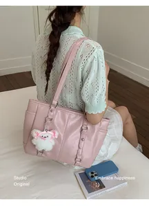 Detail of pink pleated PU leather tote bag with long straps and white plush bear charm