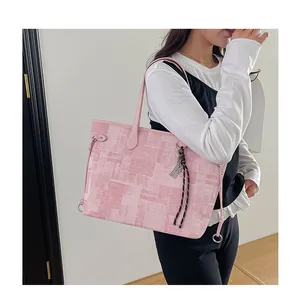 Pink tote bag detail with unique geometric texture and woven rope charm on shoulder strap