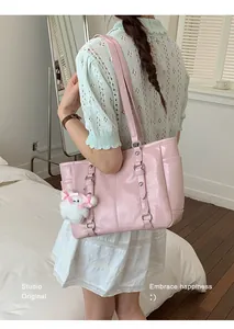 Detail of pink large capacity patent leather tote bag with plush doll and silver buckles
