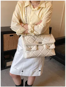Detail of cream quilted patent leather crossbody bag with chain strap and dual front pockets