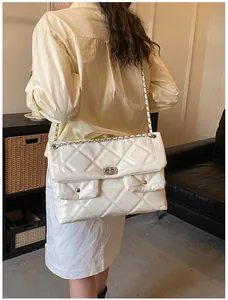 Rear view of a model wearing the large white quilted chain shoulder bag in a stylish setting