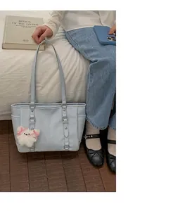 Detail of light blue faux leather tote bag with white plush rabbit and pink bow charm