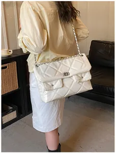 Detail of white quilted patent leather bag with chain strap and dual front pockets