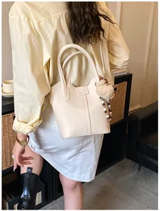 Detail view of cream bucket bag with plush bear charm and beaded chain accessory