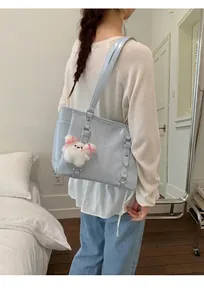Detail of light blue patent leather tote bag with a cute plush charm and shoulder strap