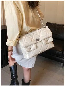 Detail of white quilted crossbody bag with dual front pockets and silver chain strap