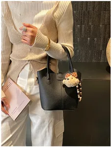 Close-up of black lychee leather bucket bag with cute bear charm and beaded detail