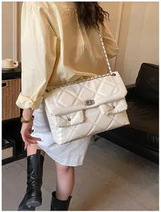 Detail view of cream quilted lacquer crossbody bag with silver chain and dual front pockets