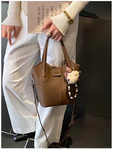 Detailed macro of brown litchi pattern leather bag with plush bear charm and beaded strap