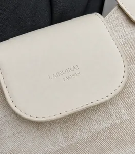 Detailed macro view of the cream leather flap with embossed logo and fine stitching