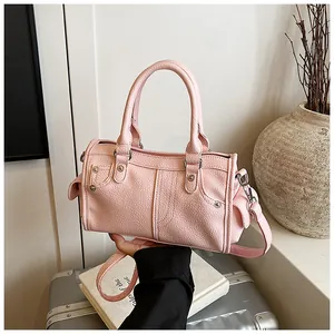 Close-up of pink lychee grain leather pillow bag with rivet details and decorative stitching