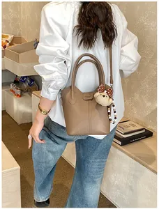 Detail of taupe pebbled leather bucket bag with cute bear charm and polka dot bow