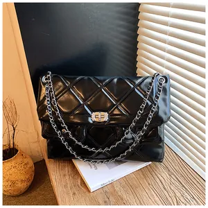 Detail of black quilted leather shoulder bag with silver chain strap and twist-lock