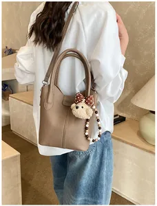 Detail of brown litchi pattern leather bucket bag with cute bear charm and bead strap