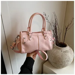 Detailed close-up of pink litchi grain boston bag with creative rivet pocket design