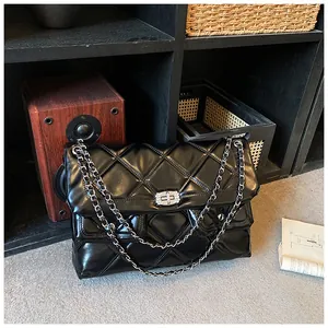 Detail view of large quilted messenger bag with silver hardware and leather chain strap