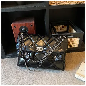Close-up of quilted black chain bag with silver twist locks on dark wood background
