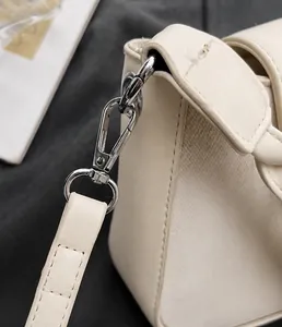 Detailed close-up of the silver metal clasp and fine stitching on the cream leather bag